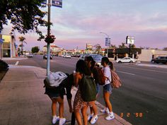 four girls are standing on the sidewalk near a street sign