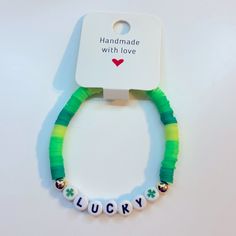 a green and white bracelet with lucky charms hanging from it's side on a white background