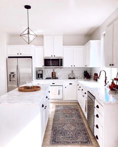 a kitchen with white cabinets and an area rug on the floor in front of the sink