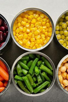 six tins filled with different types of vegetables