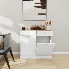 a kitchen with white cabinets and wooden flooring next to a painting on the wall