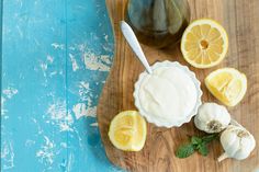 a wooden cutting board topped with sliced lemons and whipped cream next to a jar of honey