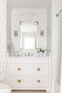 a white and gold bathroom with polka dot wallpaper