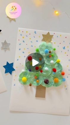 a christmas tree made out of gummy balls is displayed on a white card surrounded by stars and confetti