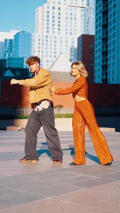 a man and woman dancing in front of tall buildings