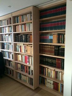 a book shelf filled with lots of books on top of wooden floor next to a window