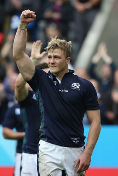 a male rugby player is holding his fist up in the air as he walks off the field