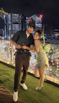 a man and woman posing for a photo in front of the city skyline at night