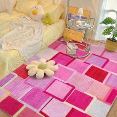 a pink and yellow rug with flowers on the floor in front of a white bed