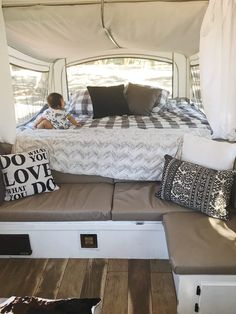 a small child sitting on top of a couch under a bed in a camper