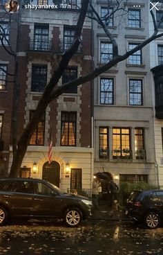 two cars parked in front of an apartment building on a rainy day with the lights on