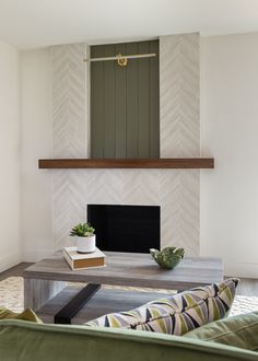 a living room with a couch, coffee table and fire place in it's center