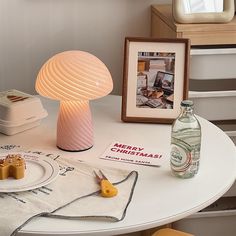 a white table topped with a lamp next to a bottle of water and other items