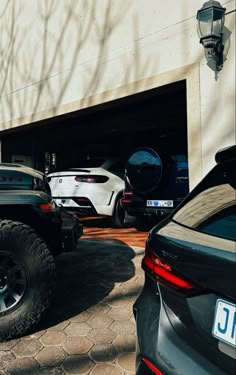 several cars parked in front of a building with two large tires on the ground next to each other