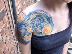 a woman with a tattoo on her chest has a wave painted on her arm and shoulder