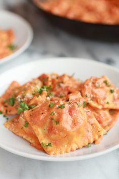 some food is on a white plate with sauce and parmesan cheese in the background