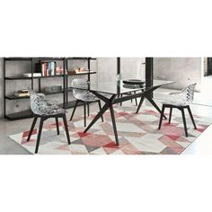 a modern dining table with chairs and bookshelves in the corner, next to an area rug