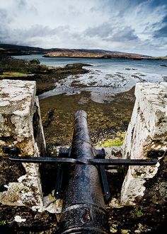 an old cannon sitting on top of a stone wall next to the ocean in scotland