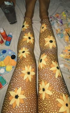 the legs and feet of a woman with yellow flowers painted on her leggings