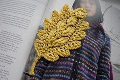 a crocheted leaf is placed on top of an open page of a book