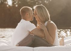 a man and woman sitting on the back of a boat kissing each other in front of water