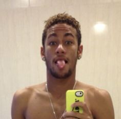 a shirtless man taking a selfie in front of a mirror with his tongue hanging out