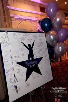 a sign that has some writing on it with balloons in the background and a star