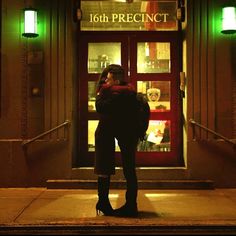 a woman standing in front of a store with her back to the camera, hugging