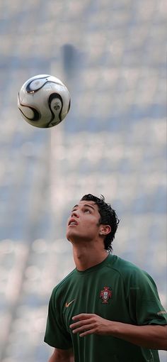 a young man is playing with a soccer ball in front of some bleachers