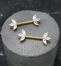 two gold barbells with crystal leaves on them sitting on top of a stone