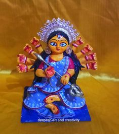 a small figurine sitting on top of a blue cloth covered floor next to a gold background