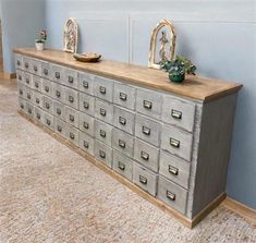 an old dresser with many drawers in the middle and two planters on each side