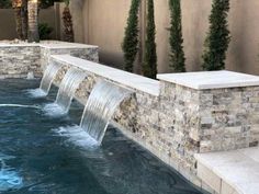 an outdoor pool with waterfall and stone walls