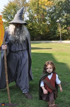 a little boy is standing next to an old wizard