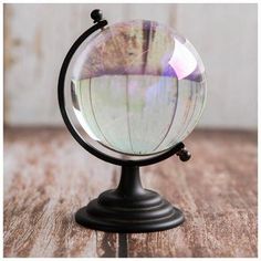 a glass globe sitting on top of a wooden table next to a black metal stand