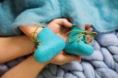 a person is holding two blue shoes with green laces on them and they are sitting on a blanket