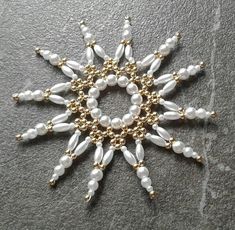 a gold and white beaded star ornament on a gray surface with pearls