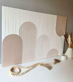 a wooden beaded necklace is sitting on a table next to a wall art piece