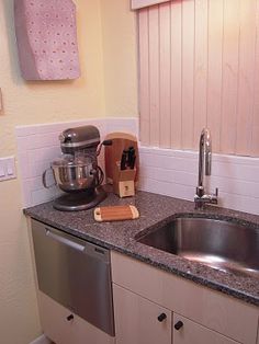 a kitchen with a sink, dishwasher and coffee pot on the counter top