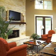 a living room filled with furniture and a flat screen tv mounted on the wall above a fire place