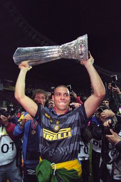 a man holding up a silver trophy in front of his head and other people around him