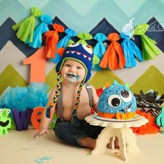 a baby is sitting on the floor in front of a cake with decorations around him