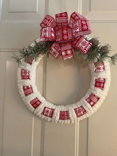 a red and white christmas wreath hanging on the front door