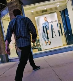 a man walking down the sidewalk in front of a gap store