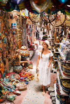 a woman walking through a market filled with lots of items