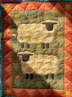 two sheep standing next to each other on a quilt