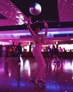 a woman is dancing with a disco ball on her head in the middle of a dance floor