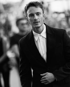 a black and white photo of a man in a tuxedo looking at the camera