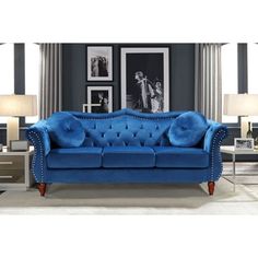 a blue couch in a living room with pictures on the wall and two lamps next to it