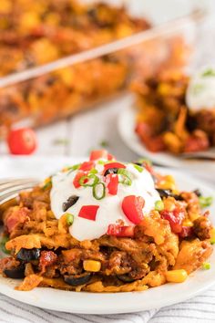 a white plate topped with mexican casserole covered in sour cream and toppings